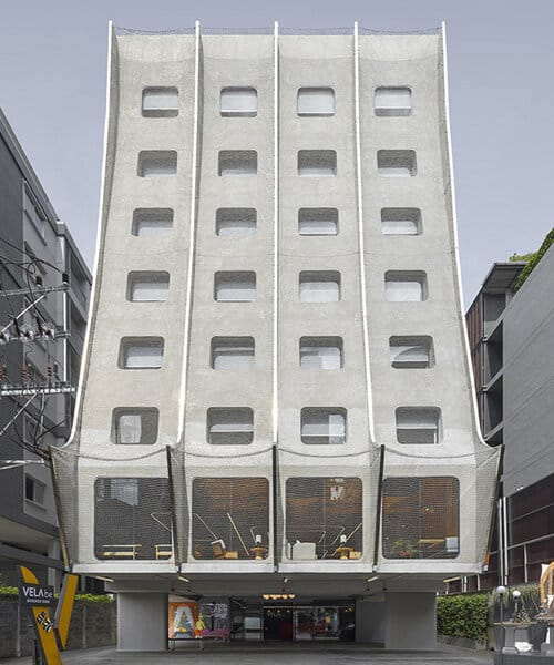 واجهة فندق Vela be Siam في بانكوك، بتصميم فولاذي مغطى بسلاسل معدنية لامعة تعكس الإضاءة.