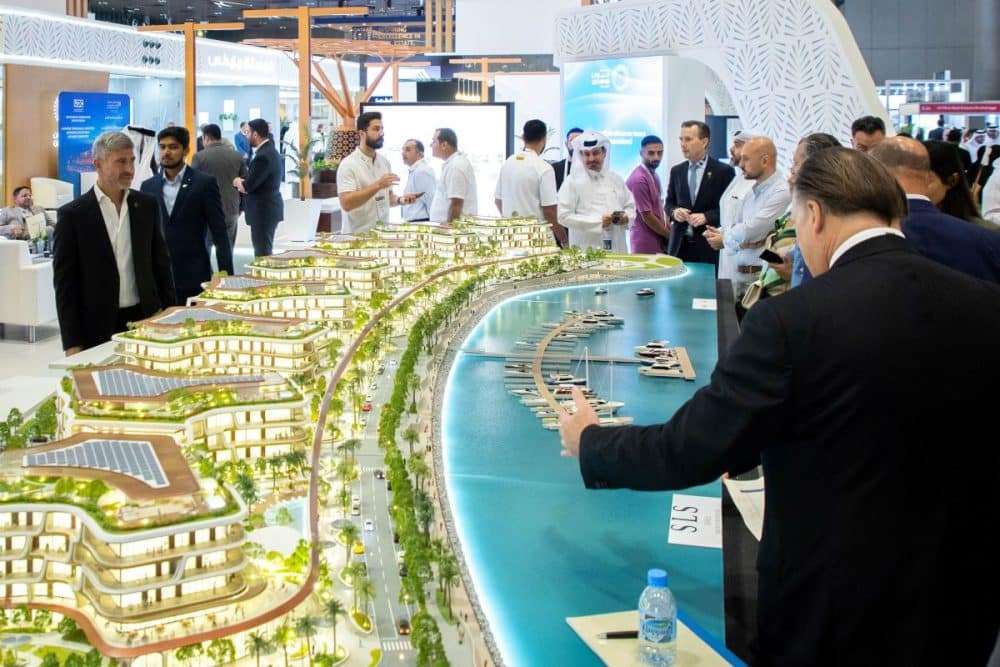 زوار يتفقدون مجسم معماري لمشروع عقاري على الواجهة البحرية خلال معرض سيتي سكيب قطر 2025.