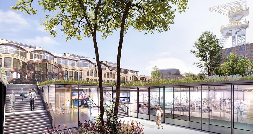 Modern glass-fronted public space surrounded by historic industrial buildings as part of the Wieczorek redevelopment project.