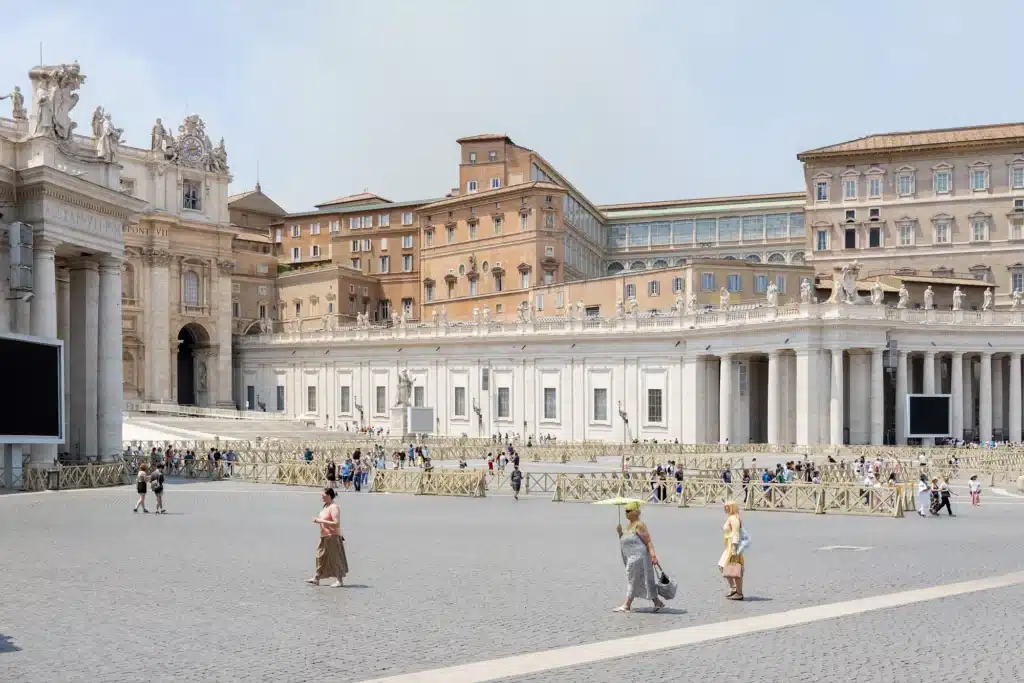 Street scene in historic Rome showing people moving through a space framed by traditional architecture.