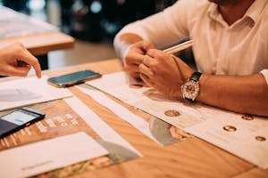 Two adults discussing a menu at a restaurant table with chopsticks and phones.