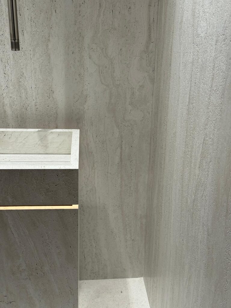 Light grey stone-textured wall and floor with a minimalist modern sink