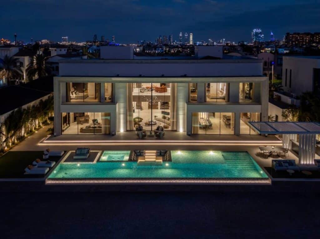 Night view of a villa with illuminated fa&ccedil;ade, pool, and Atlantis The Royal backdrop