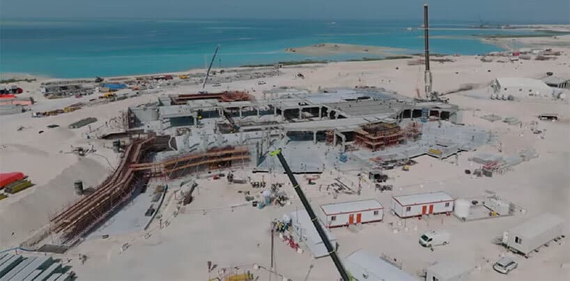 On-site construction on the island with pathways and horizontal structures defining spatial zones.