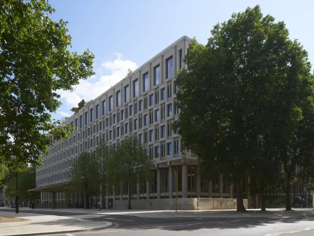 الواجهة الأمامية للمبنى المحاط بالأشجار، مما يضفي طابعًا طبيعيًا على التصميم.