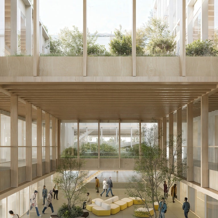 Bright, airy indoor courtyard with wooden beams, greenery, and people walking or relaxing on colorful modular seating.