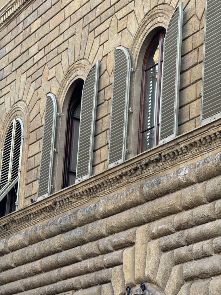 A simple, framed window on a historic stone building in Florence, suggesting a quiet residential street.