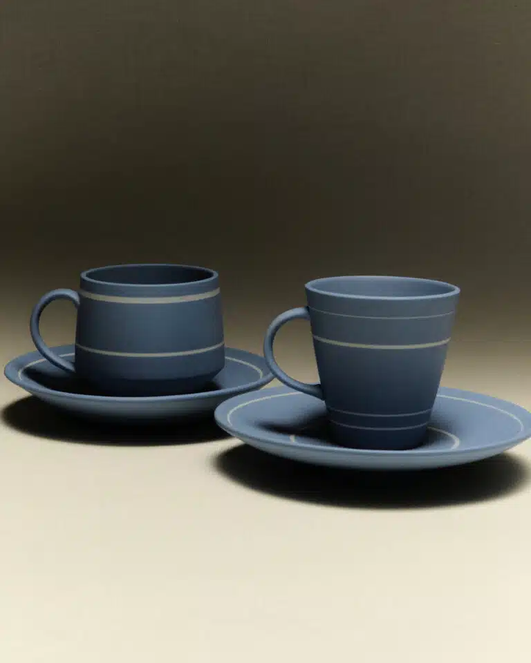 Blue cups with white horizontal lines, resting on blue plates with white lines around the border