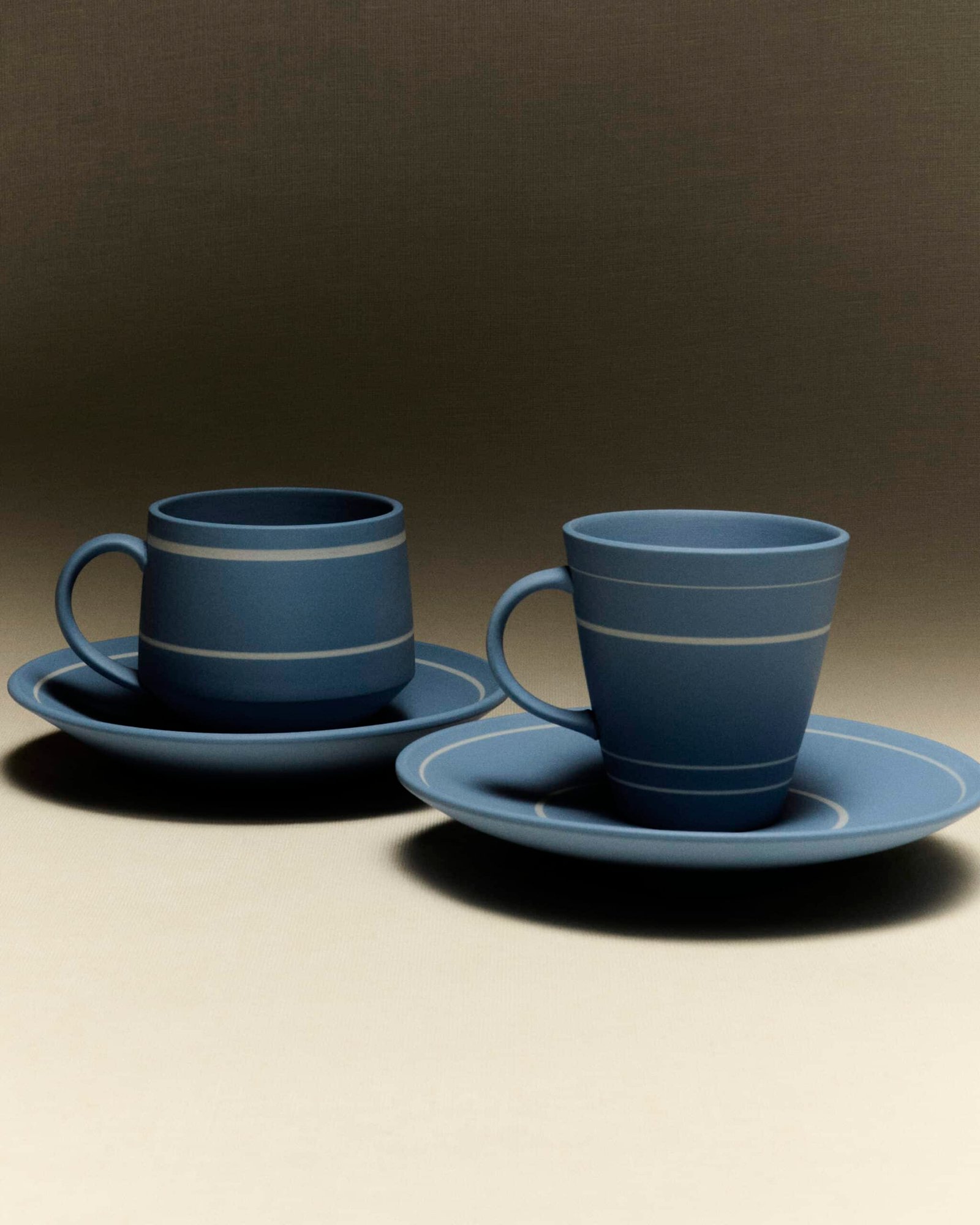 Blue cups with white horizontal lines, resting on blue plates with white lines around the border