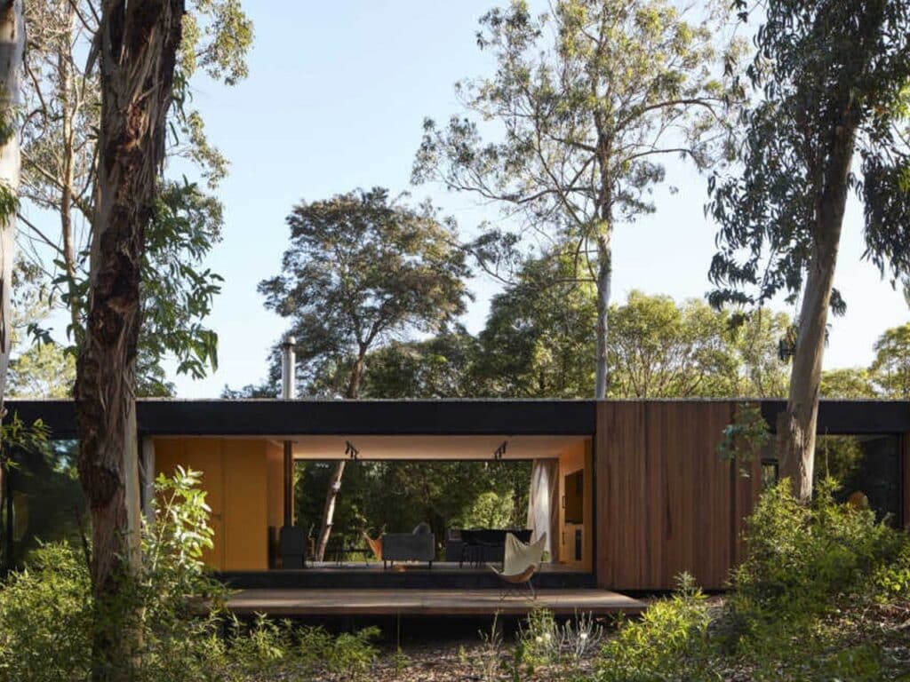 Nighttime illumination transforming Iside house into a warm, glowing beacon among trees.