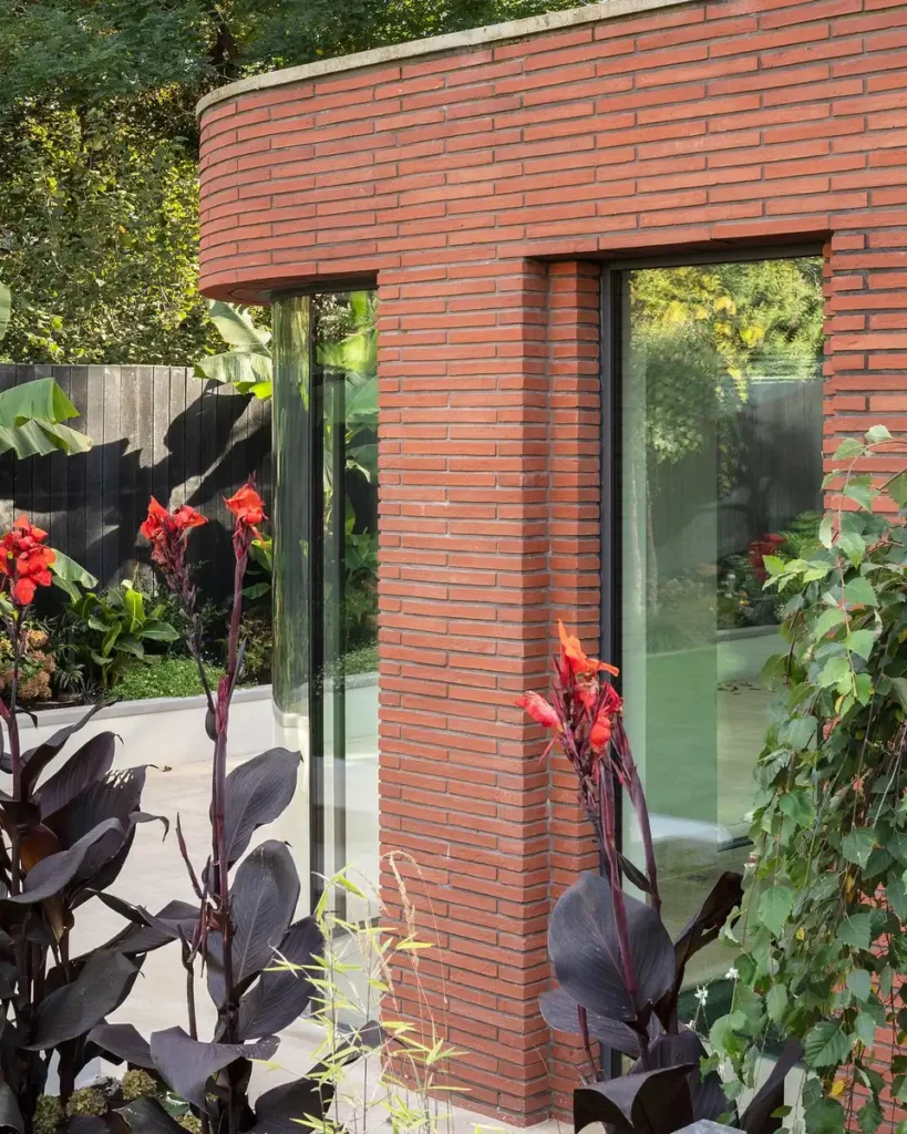 A calm brick pavilion nestled in a lush green garden, surrounded by trees and soft light.
