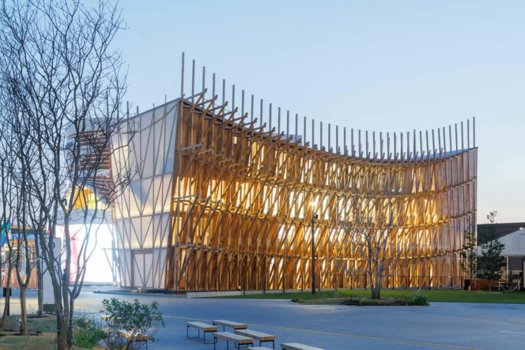 Exterior view of Bahrain Pavilion at Expo Osaka 2025 designed by Lina Ghotmeh, showcasing wooden fa&ccedil;ade and natural ventilation concept.