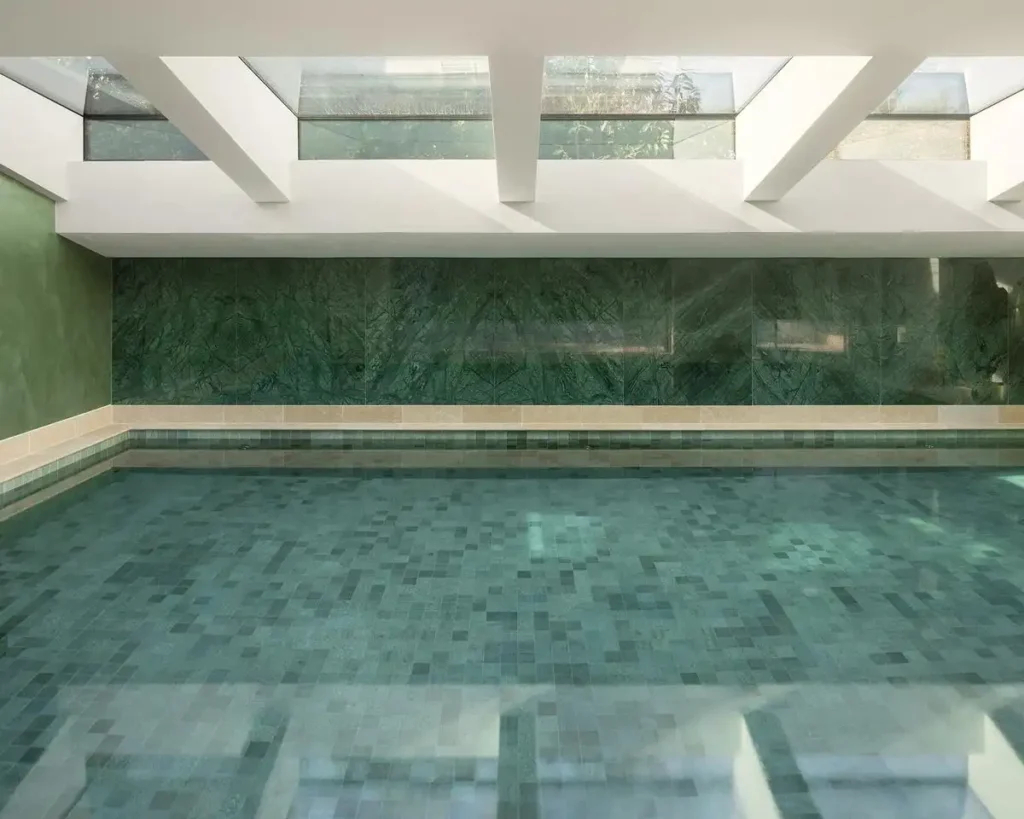 Indoor pool with green marble walls and a glass ceiling, flooded with natural light.