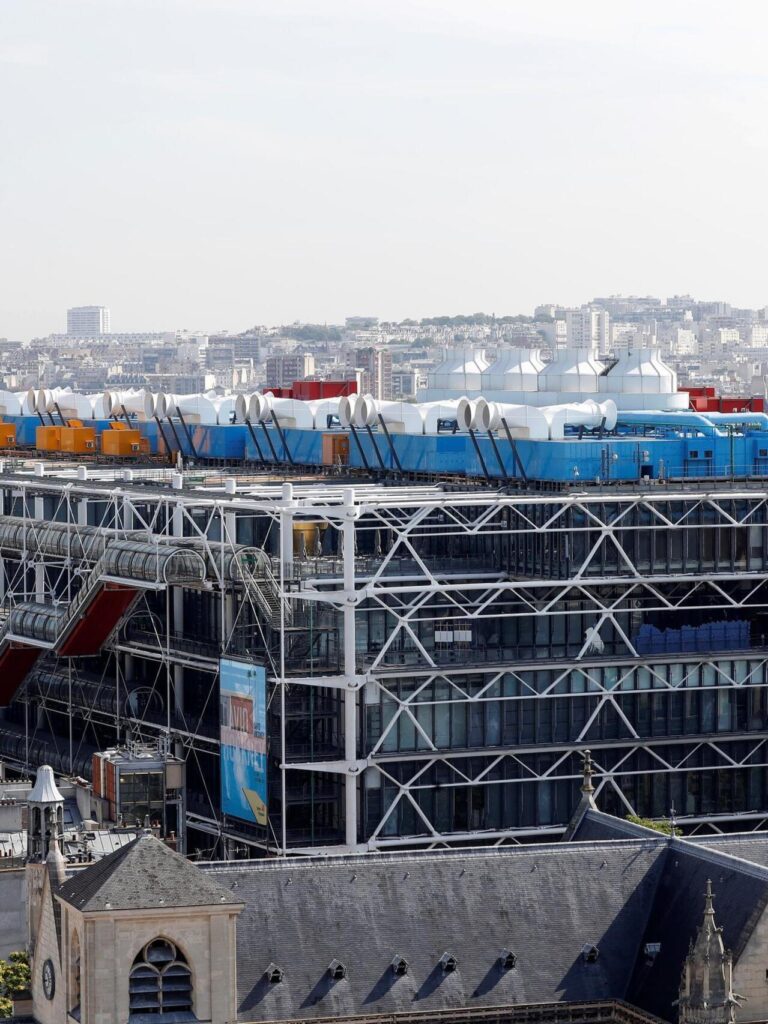 Aerial view of Centre Pompidou&rsquo;s blue & white roof against Paris skyline.