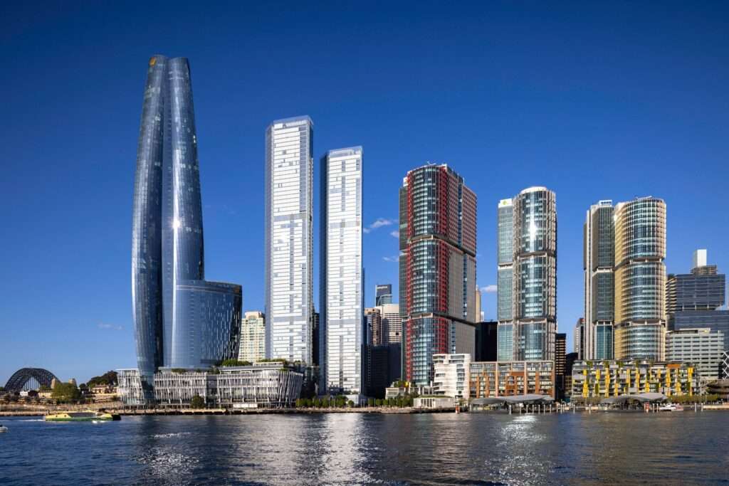 Barangaroo skyline: sleek glass towers rise above Sydney Harbour, with the Harbour Bridge in the distance.