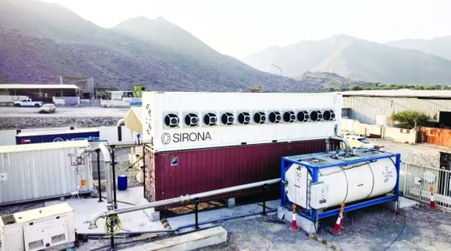 وحدة احتجاز كربون معيارية تحمل علامة Sirona، مبنية من حاويات شحن، جاهزة لتنظيف الهواء أمام خلفية جبلية.