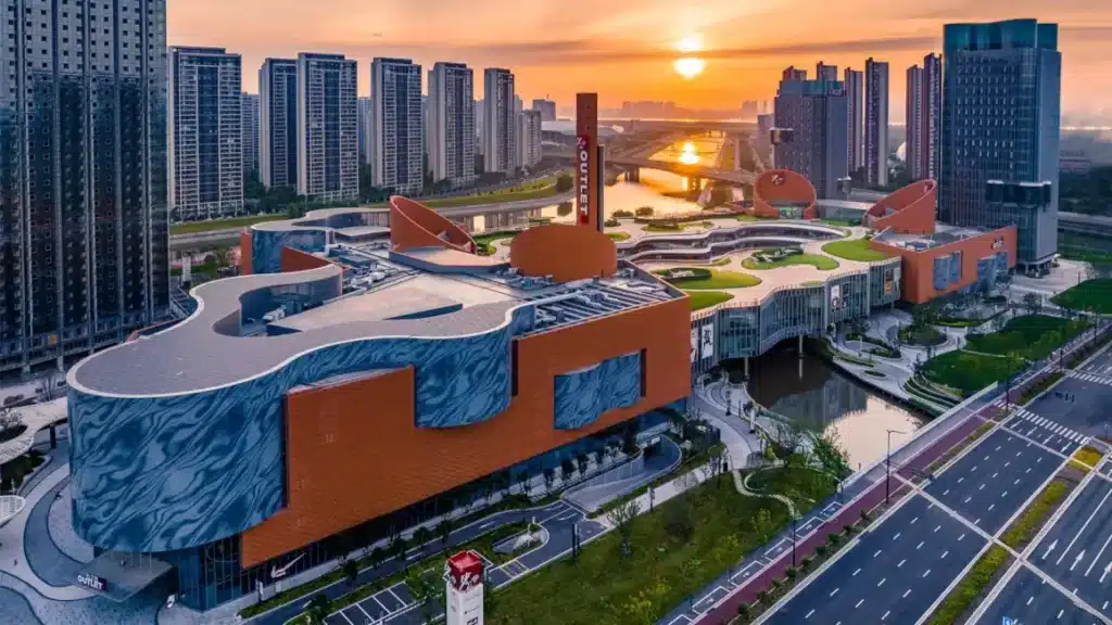 Chengnan Riverfront Complex at sunset — curved buildings, river weaving through, bridges connecting everything.