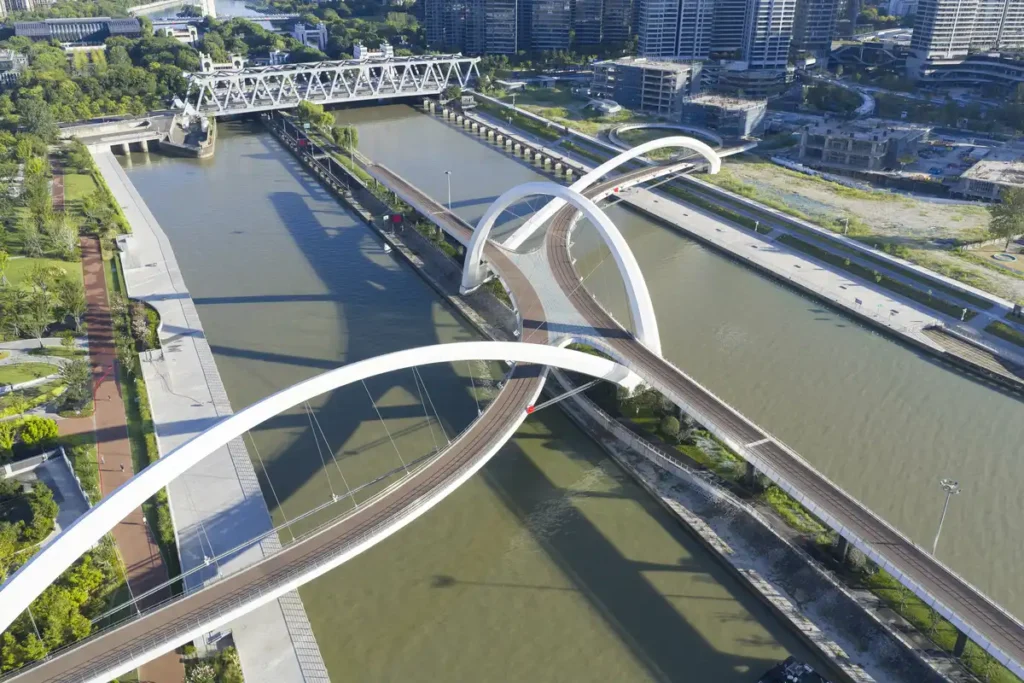 Aerial view of Hangzhou’s Grand Canal Gateway Bridge — a fluid white ribbon weaving over water, bridging modernity and heritage.