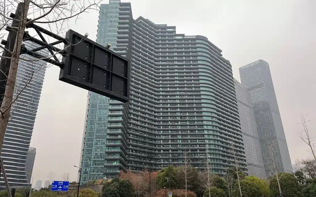 منظر جانبي للبرج يُظهر الشكل المنحني وتكامل الوحدات مع المساحات الخضراء المحيطة.