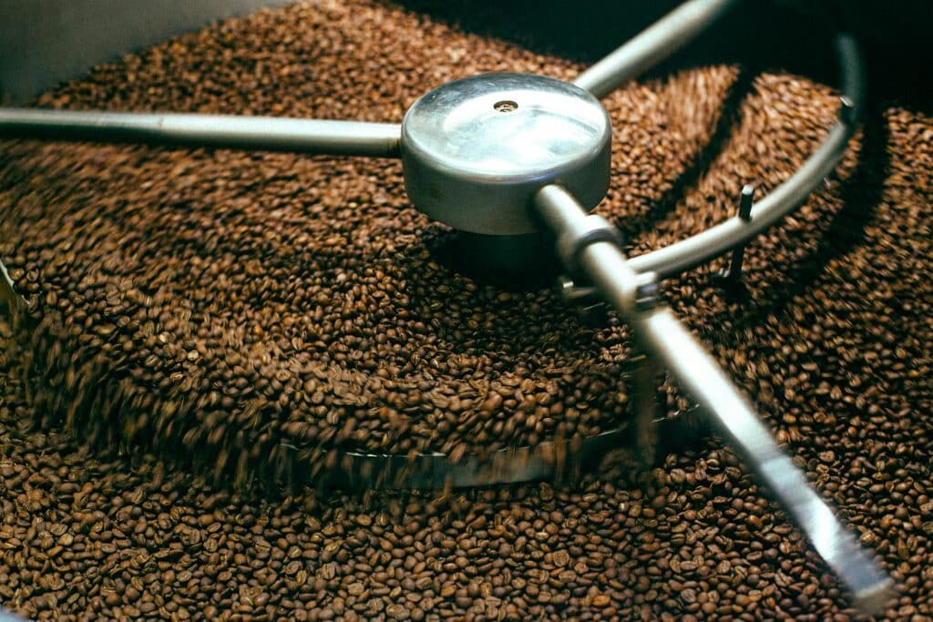 Coffee beans tumbling inside a roaster &mdash; the moment they begin their journey from morning brew to sustainable building material.