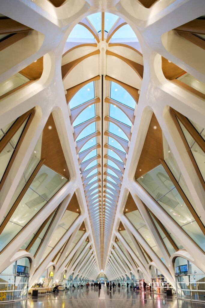 Inside Mons station — white bone-like ceiling with wood accents and skylights.
