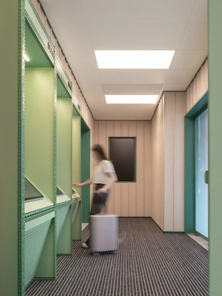 Self-service check-in area at Hi Inn featuring digital kiosks integrated into a minimal architectural setting.