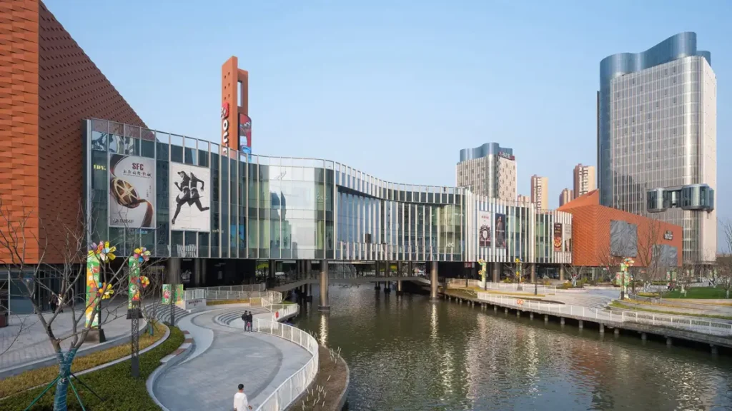 Chengnan’s facade — warm terracotta walls meet flowing, wave-like glass under a clear blue sky.