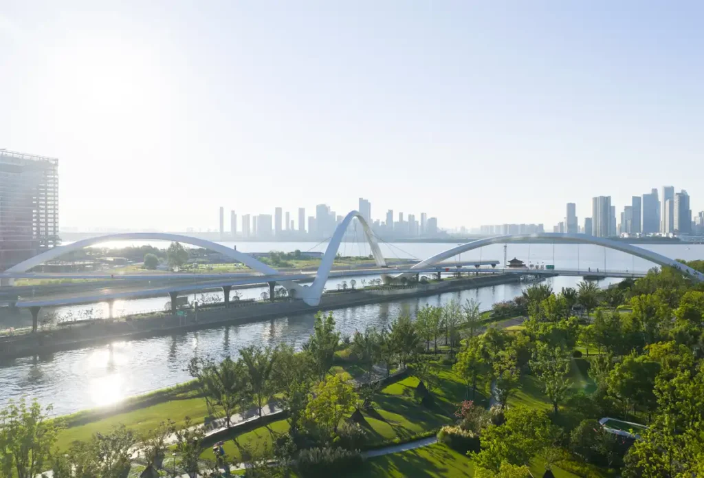 Grand Canal Gateway Bridge at sunrise — a graceful white arc gliding over water, framed by greenery and the modern skyline.