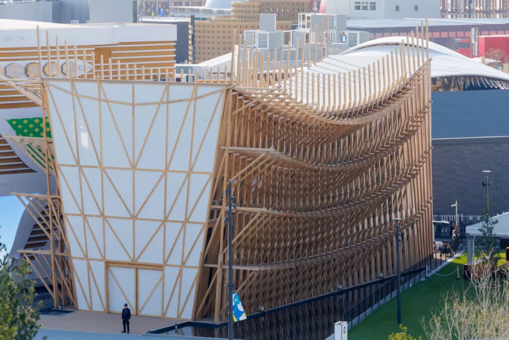 Interior view of Bahrain Pavilion showing the interplay of light and shadow through wooden lattice walls.