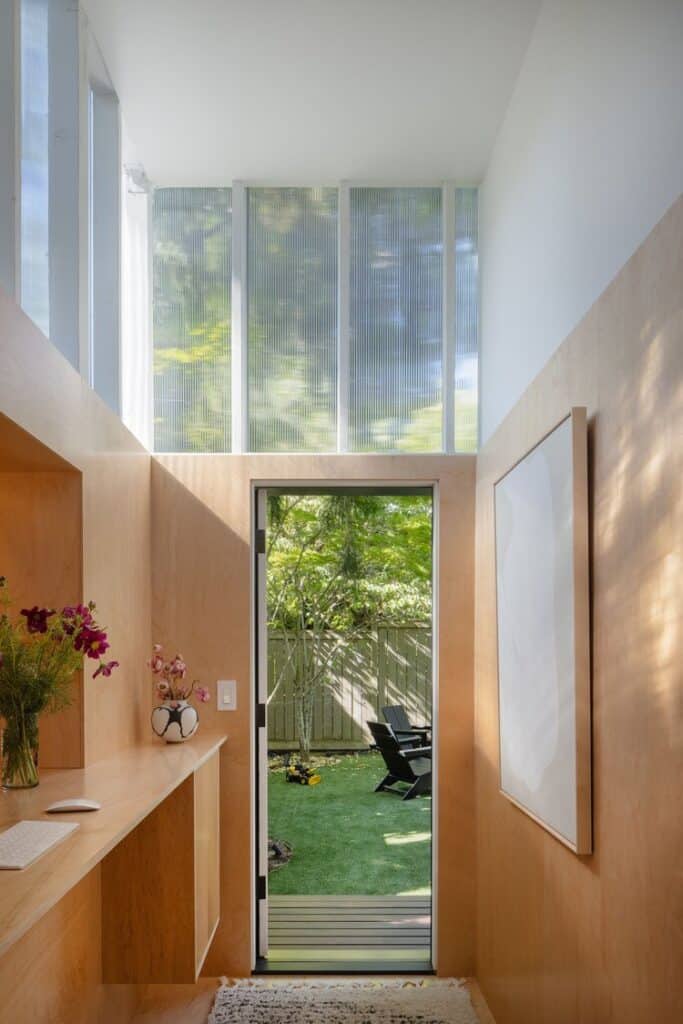 مكتب أنيق بجدران خشبية وباب زجاجي يفتح على الفناء الأخضر.