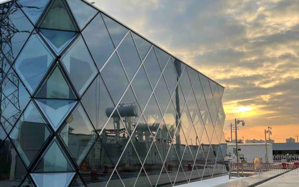 Geometric glass facade reflecting sunset sky.