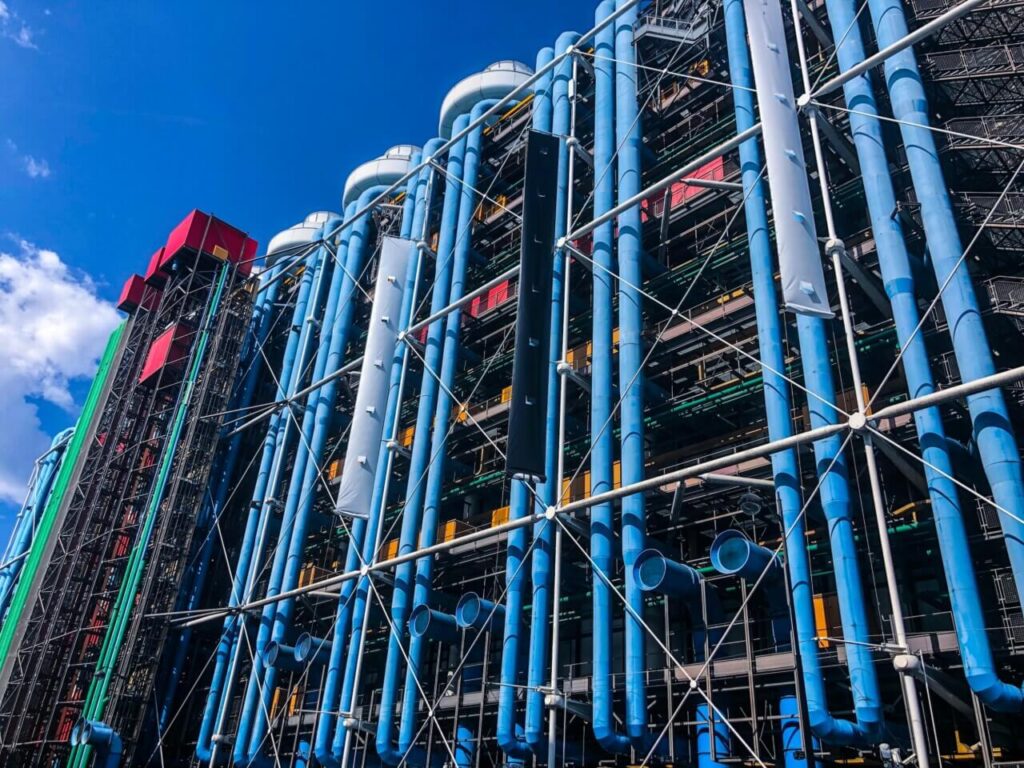 Close-up of Centre Pompidou&rsquo;s iconic blue pipes and steel frame against a clear sky.