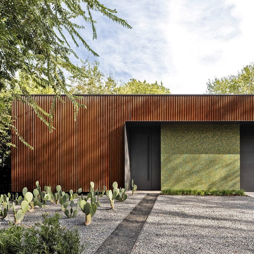 واجهة معدنية بخطوط رأسية مع باب أسود وحديقة صبار.واجهة معدنية بخطوط رأسية مع باب أسود وحديقة صبار.