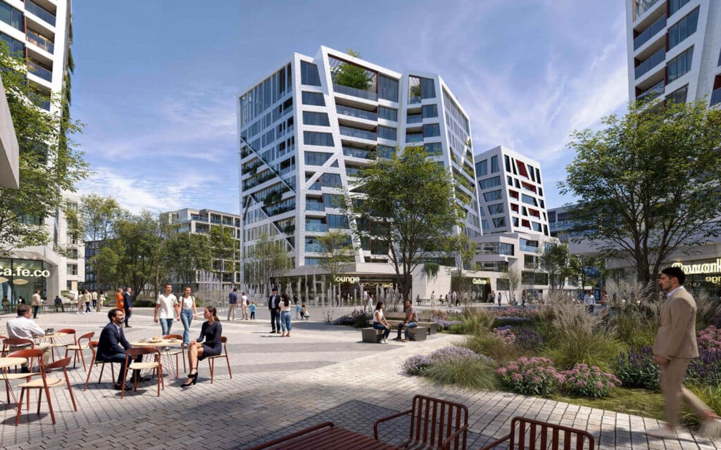 A sunny public square in Prague with modern apartments, outdoor seating, and people enjoying the day.