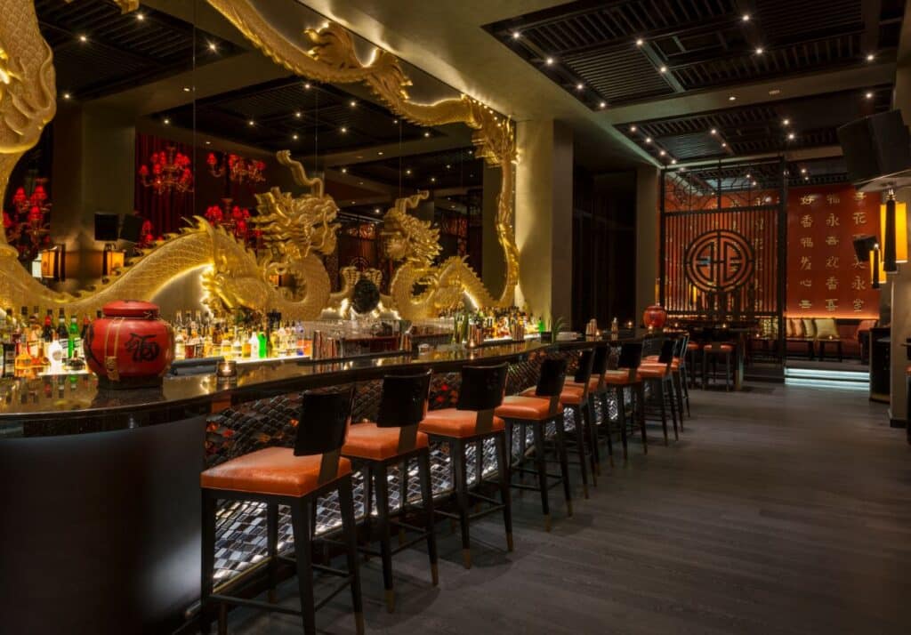 تصميم داخلي لردهة بودا بار في جزر العالم بدبي يعكس مزيجًا من الطابع الآسيوي الفاخر والإضاءة الدافئة.