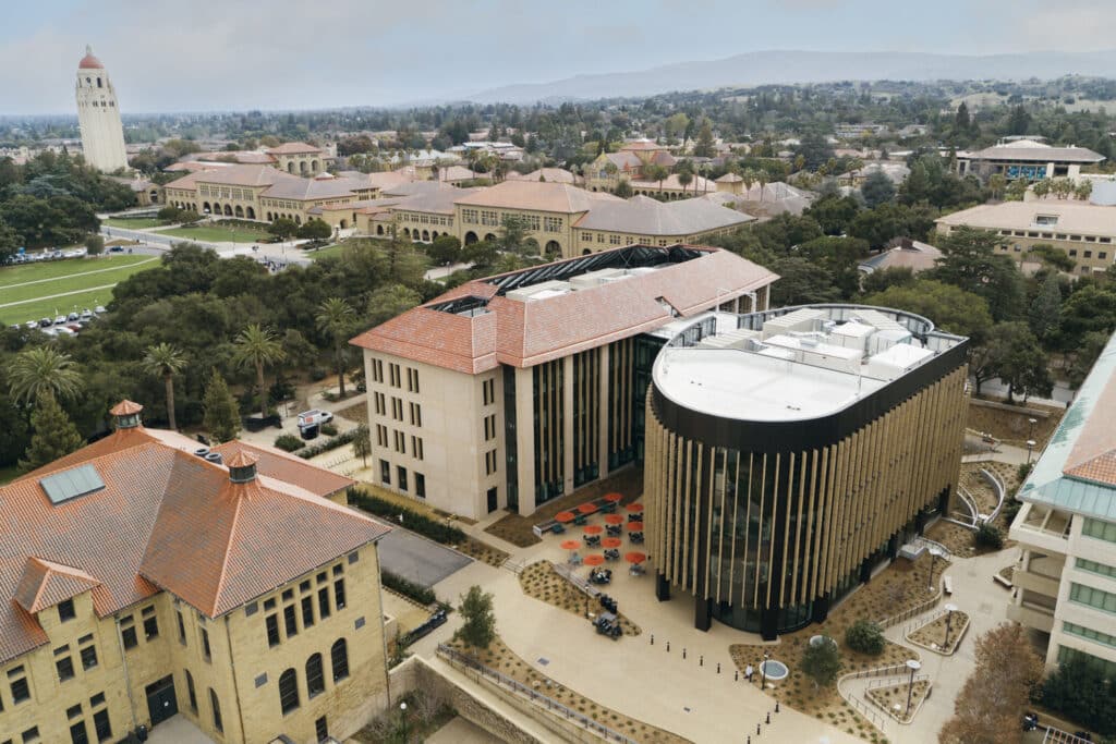Aerial view of Stanford&rsquo;s new building nestled among historic campus architecture, with Hoover Tower in the distance.