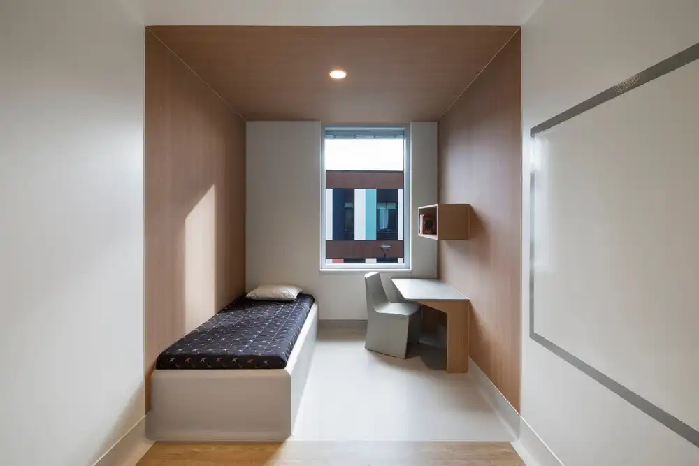 Small, calm bedroom at CRJDA Sainte-Thérèse with bed, desk, and window for privacy.