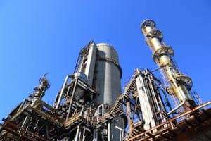 A towering industrial plant under a vivid blue sky, showcasing its intricate architecture and industrial prowess.