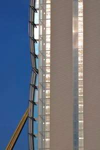 Close-up of a modern skyscraper facade featuring glass and metal elements against a blue sky.