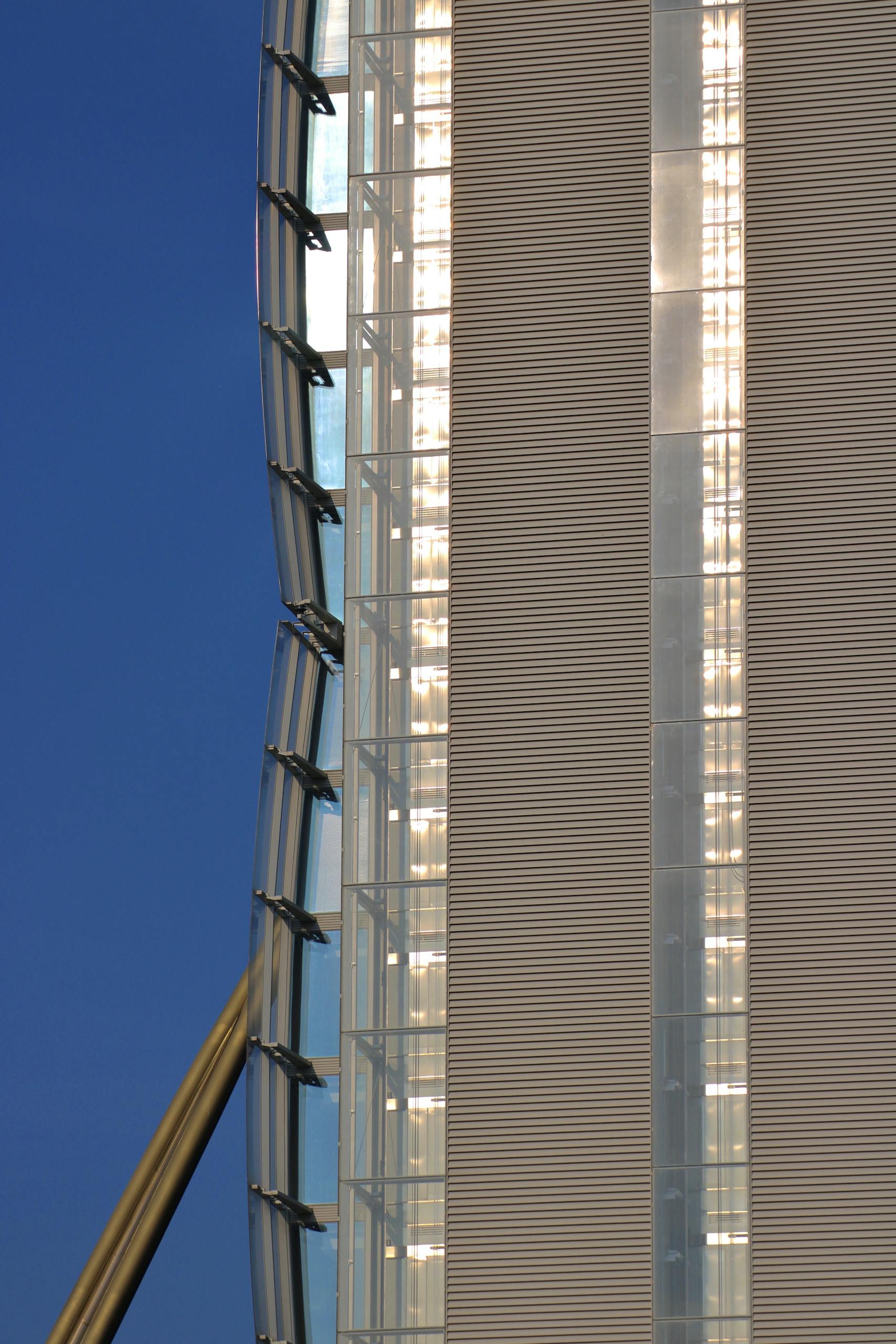 Close-up of a modern skyscraper facade featuring glass and metal elements against a blue sky.