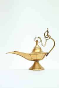 Elegant golden Aladdin's lamp with intricate handle on a clean white backdrop.