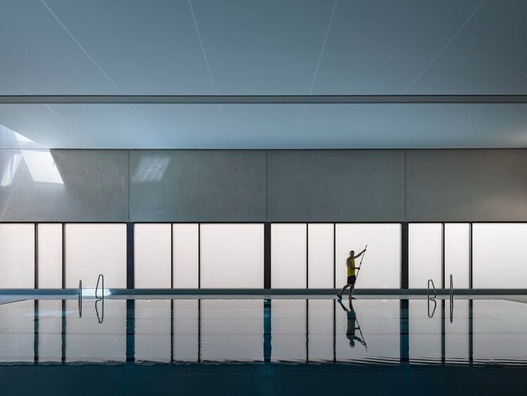 Indoor swimming pool at Sportbad am Rabet project in Leipzig, showing modular design, use of glass and exposed concrete, and open spaces integrated with nature and urban context.