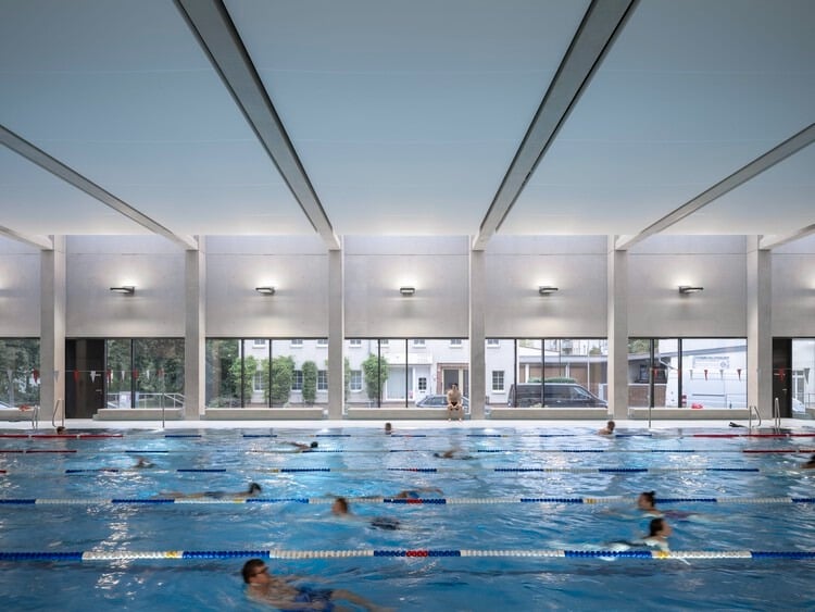 Indoor swimming pool at Sportbad am Rabet project in Leipzig, showing modular design, use of glass and exposed concrete, and open spaces integrated with nature and urban context.