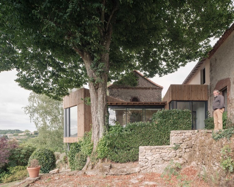Exterior view of Clos Saint-Martin project blending historical stone buildings with modern wooden extensions and landscaped terraces.
