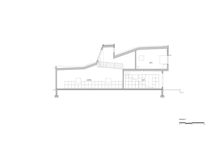 L-shaped house fa&ccedil;ade clad in corrugated aluminum reflecting sunlight