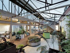 Interior design and architectural transformation of an industrial warehouse with indoor courtyard, floating mezzanines, sustainable materials, and practical furniture layout