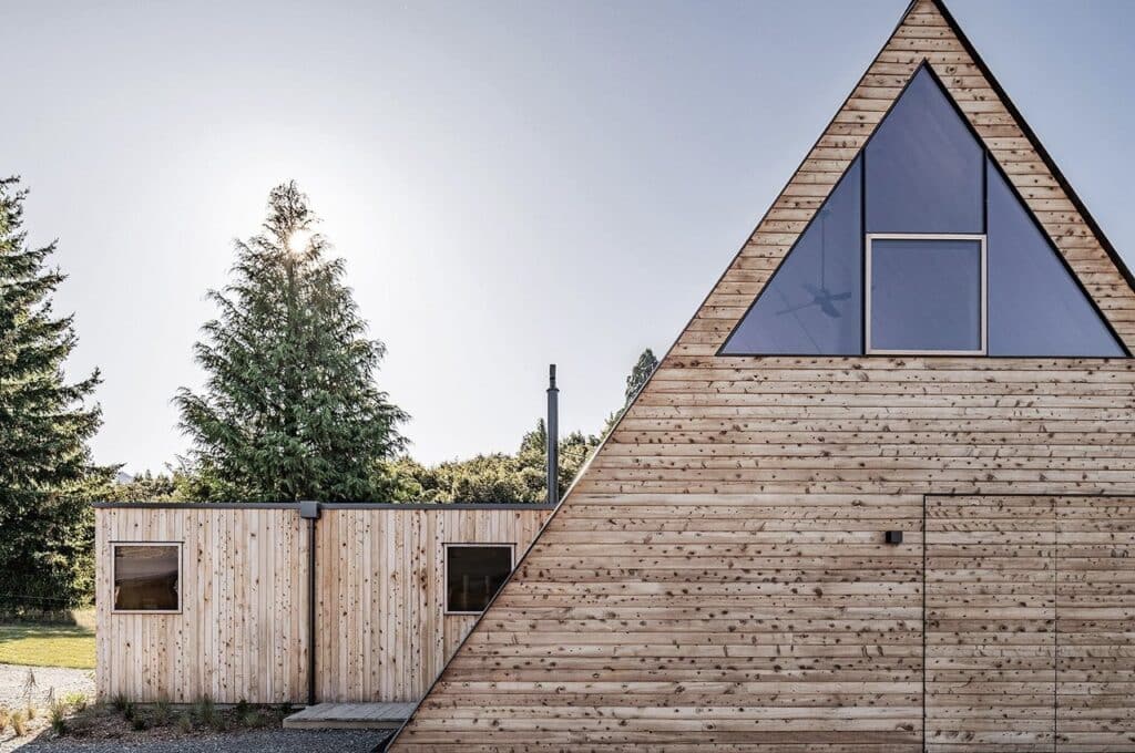 Exterior view of Adventure Whare resort surrounded by trees and forests, featuring traditional A-frame design with modern touches.