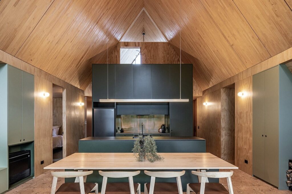 Exterior view of Adventure Whare resort surrounded by trees and forests, featuring traditional A-frame design with modern touches.