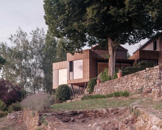 Exterior view of Clos Saint-Martin project blending historical stone buildings with modern wooden extensions and landscaped terraces.
