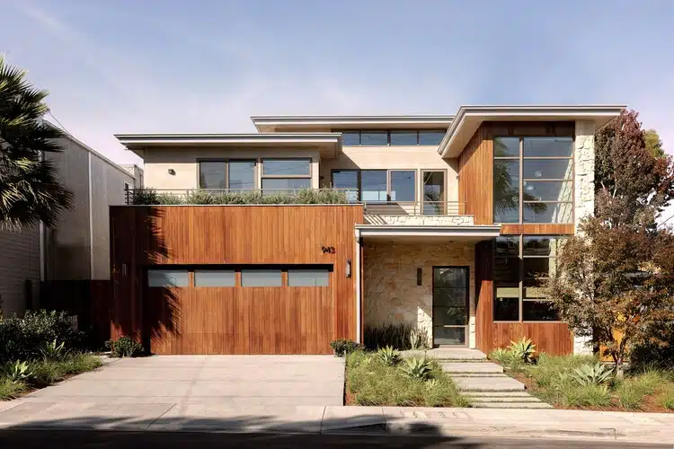 Renovated farmhouse exterior featuring integrated stone, wood, and stucco, showing material contrast.